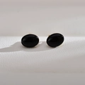 Macro shot of oval black agate stud earrings with polished gold-tone metal base - Black