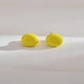 Macro shot of oval bright yellow pearl earrings on white textured leather background - Yellow