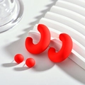 Vue macro des boucles d'oreilles en acrylique rouge mat et des clous assortis sur un support - Rouge
