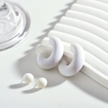Détail de boucles d'oreilles créoles C en acrylique blanc mat et clous sur support - Blanc