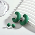 Détail de boucles d'oreilles en acrylique vert mat en forme de C et boule sur socle blanc - Vert clair