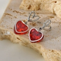 Dettaglio macro di orecchini a cuore in argento con cristalli rossi su sfondo di pietra - Pendaglio a Cuore (B0137) / Colore Argento Rosso