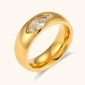 Gros plan d'une bague dorée polie ornée d'un zircon marquise sur fond beige épuré - US 6 / Style Zircon Marquise