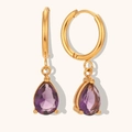 Gros plan de boucles d'oreilles créoles dorées avec pendentifs en zircon violet - Violet