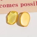 Dettaglio macro di orecchini in resina gialla con lucentezza occhio di gatto e forma ovale - Giallo