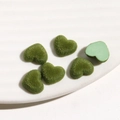 Detailopname van groene hartvormige geflockte bedeltjes voor DIY sieraden op bord - Groen