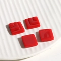Macro view of red square resin jewelry charms with layered geometric design on ceramic tray - Square / Red
