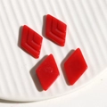 Macro detail of red resin rhombus jewelry charms with V-shaped texture on white ceramic tray - Diamond / Red