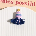 Détail d'un pompon en coton fait main avec boucle dorée présenté sur une assiette en céramique - Bleu foncé