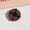 Makro-Detail von dunkelbraunem runden Holzknopf mit Spiraltextur und schwarzem Knoten - Schwarzer Knoten