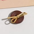 Nahaufnahme eines braunen Holzknopfs mit goldener Schleife für Mäntel und DIY-Projekte - Schleife Gold