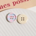 Macro detail of round four-hole wooden buttons with pink checkered print and cream texture - Pale Blue