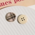 Detailed view of checkered and natural wooden four-hole buttons on a ceramic plate - Grey Coffee