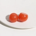 Macro shot of two glossy orange resin dome charms for DIY hair accessories and jewelry - Orange