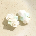 Vue macro de boucles d'oreilles roses en céramique blanc nacré avec feuilles vertes - Vert clair