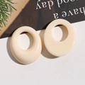 Close-up of cream white oval hollow resin earrings with minimalist geometric design - White