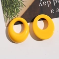 Macro shot of bright yellow thick oval resin earrings with smooth high-gloss surface - Yellow
