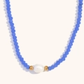 Makroaufnahme von königsblauen Kristallperlen und einer weißen Süßwasserperle auf Goldkette - Dunkelblaue Jade-Perlen