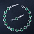 Detailed macro of silver bracelet with green circular stones in heart-shaped settings - Green