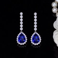 Macro shot of silver bridal earrings featuring blue pear-cut zircon with halo setting - Blue