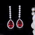 Detail of elegant silver drop earrings with pear-cut red gems and white zircon halo - Red