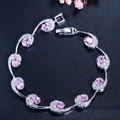 Macro detail van zilverkleurige schakelarmband met ovale roze steen en pavé diamanten - Roze