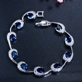 Elegante zilveren armband met ovale blauwe saffieren en CZ-stenen op een zwarte achtergrond - Blauw