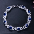Bracelet en argent avec pierres bleues ovales et halo de zircon blanc sur fond noir - Bleu saphir