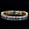 Elegante pulsera tennis bañada en oro con circonitas cuadradas sobre fondo reflectante negro - Blanco
