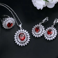 Detail shot of silver sunflower jewelry set with red gemstones on black leather - Red