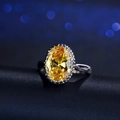 Elegante zilveren ring met grote ovale gele zirkoon en halo-zetting op een donkere basis - US 6 / Goudgeel