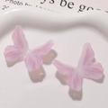 Detailaufnahme von rosa glitzernden Schmetterlings-Anhängern auf einem Keramikteller - Hellrosa