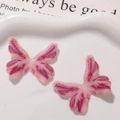 Detail von glitzernden Harz-Schmetterlingsanhängern in Pink und Lila für DIY-Schmuck - Rosenrot