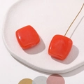 Detailed macro view of orange resin cube charms with smoke texture and gold wire accents - Orange