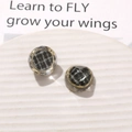 Close-up of vintage resin charms with black plaid fabric inlay and gold metal edges - Gray