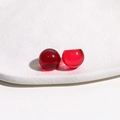 Detailed macro view of two translucent red 14mm round resin cabochons on white textured background - 1 Piece / Red