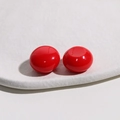 Close-up of polished 18mm red resin dome cabochon on a white tray for jewelry making - Red