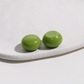 Close-up of shiny grass green round resin beads on a white textured display tray - 1 Piece / Green