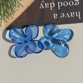 Macro detail of blue translucent acrylic four-petal flower charms for DIY jewelry making - Blue