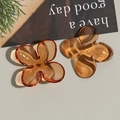 Detailed macro view of two amber acrylic four-petal flower charms for DIY jewelry making - Brown