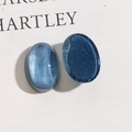 Makro-Detail von ovalen blauen Kunstharzohrsteckern mit Glitzer und Jelly-Effekt - Blau