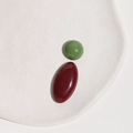 Close-up of glossy oval resin cabochons in olive green and burgundy colors - Green Half Ball + Red Oval