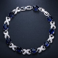 Macro shot of silver bracelet featuring oval blue zircons and X-shaped diamond accents - Blue