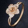 Elegant gold-tone rose cuff bracelet with sparkling white zircon pavé on a black background - Gold