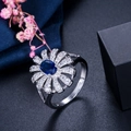 Macro-opname van zilveren bloemring met blauwe ovale steen en witte zirkonia's - Maat 6 / Blauw