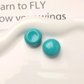 Macro detail of glossy teal resin cabochons on a white decorative ceramic tray - Lake Green
