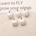 Macro shot of five white glossy resin tooth charms with silver loops for DIY jewelry - Tooth With Silver Pendant Loop