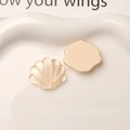 Macro detail of shell-shaped resin charms with amber translucent and cream matte textures - White