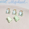 Macro detail of iridescent and pastel green mini bear charms on a beige tray - 1 Piece / Green