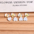 Macro shot of 8 aurora crystal and white heart-shaped nail art charms on wood - 1 Piece / White Blue